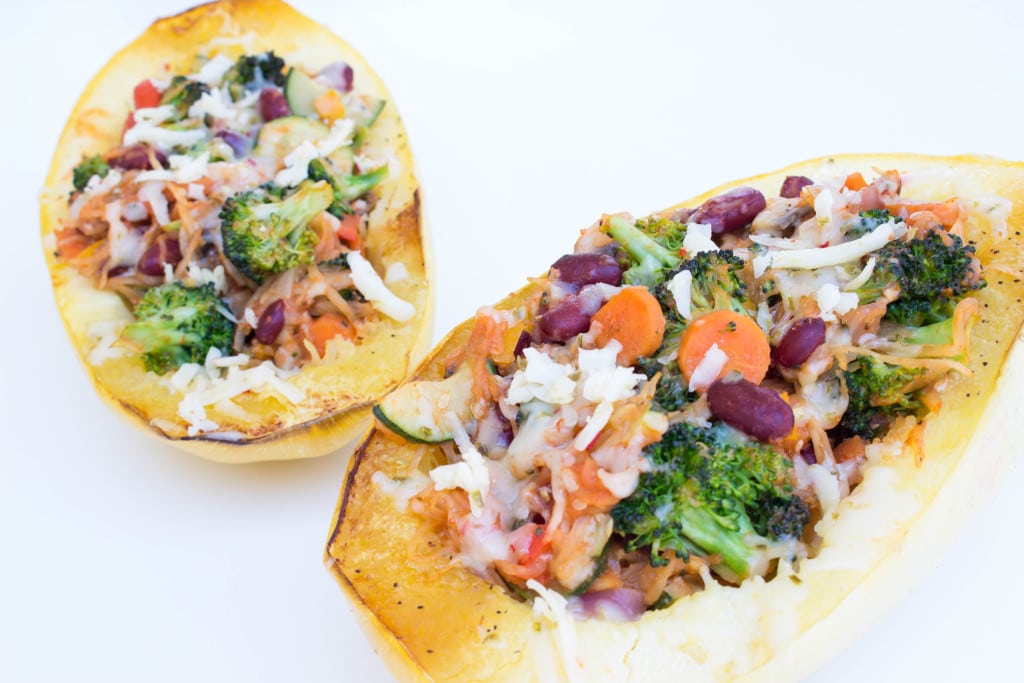 spaghetti squash on a white board filled with veggies and cheese