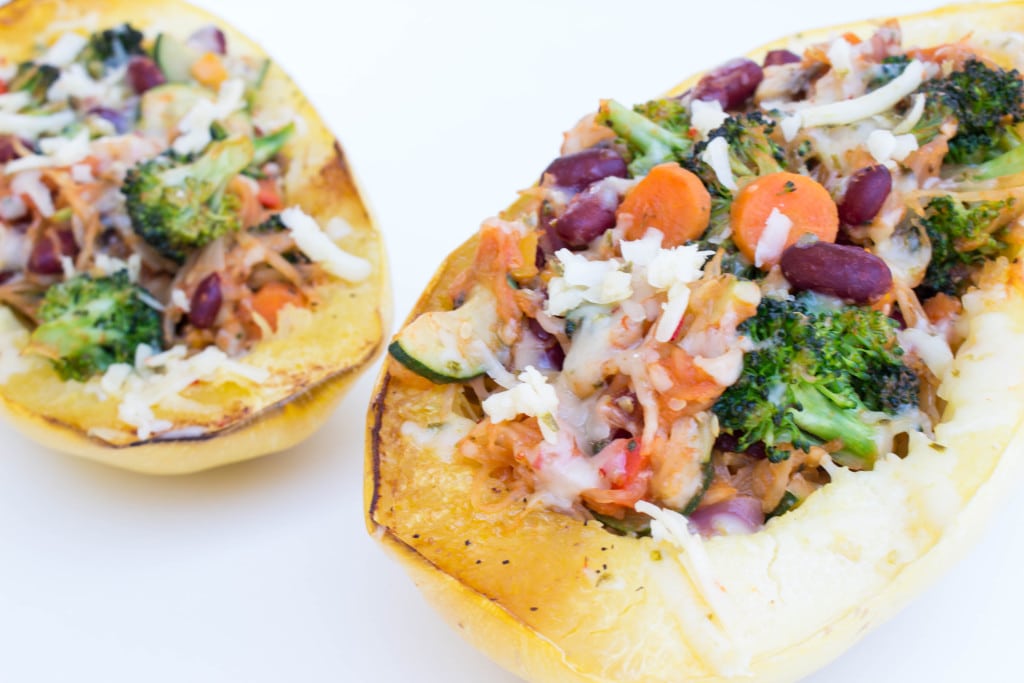 spaghetti squash on a white board filled with veggies and cheese