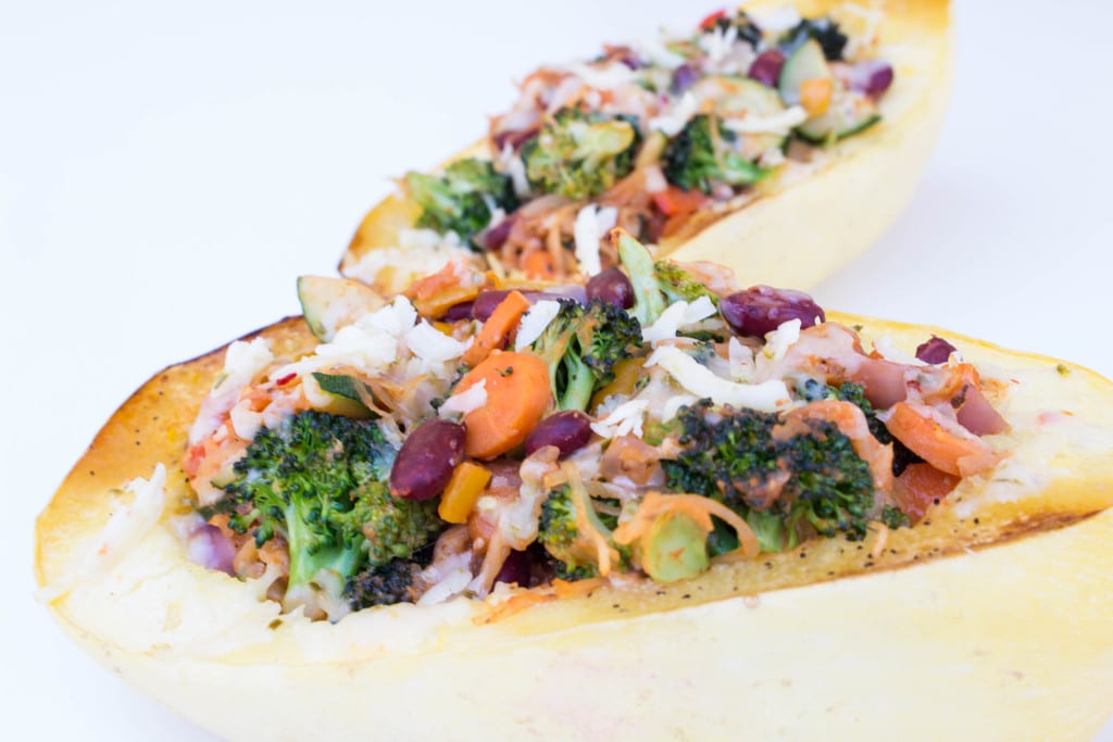 spaghetti squash on a white board filled with veggies and cheese