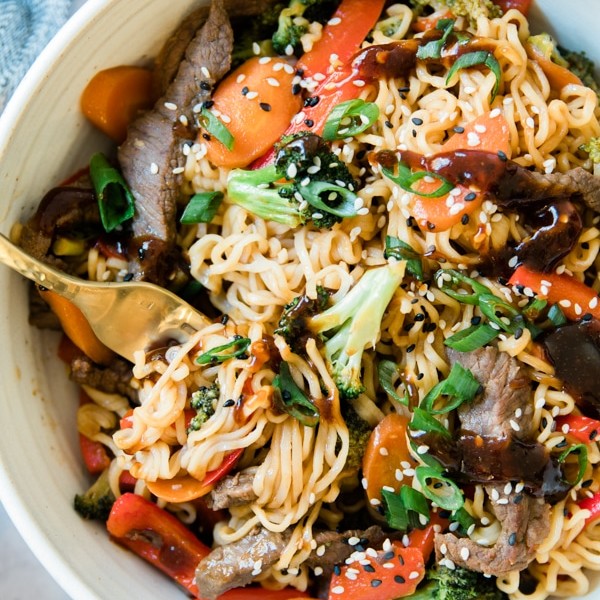 stir fry in a white bowl with steak and ramen noodles