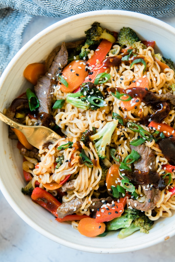 stir fry in a white bowl with steak and ramen noodles