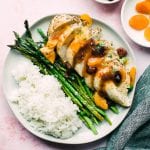 chicken on a white plate with rice and asparagus