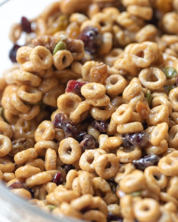 cheerios mixed with dried fruits and nuts in a large glass bowl