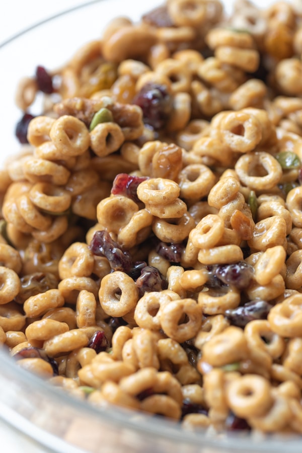 cheerios mixed with dried fruits and nuts in a large glass bowl for cheerio trail mix 