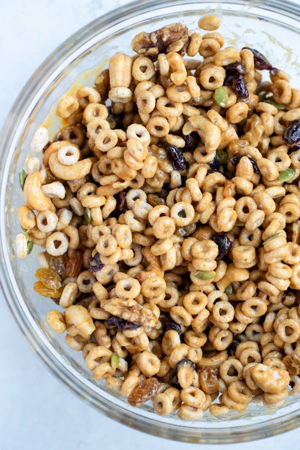 cheerios mixed with dried fruits and nuts in a large glass bowl 
