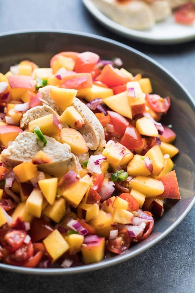 peach salsa in a gray bowl topped with chicken