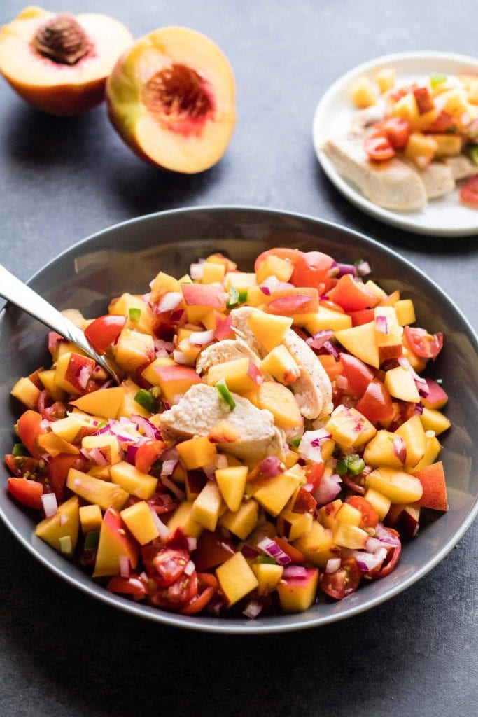 peach salsa in a gray bowl topped with chicken