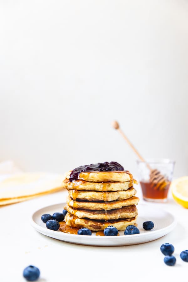 lemon blueberry pancakes stacked on a white plate