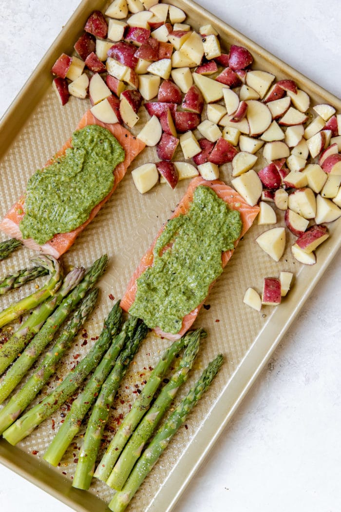 salmon with veggies on a gold sheet pan