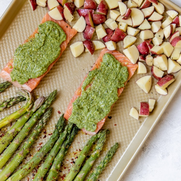 salmon with veggies on a gold sheet pan