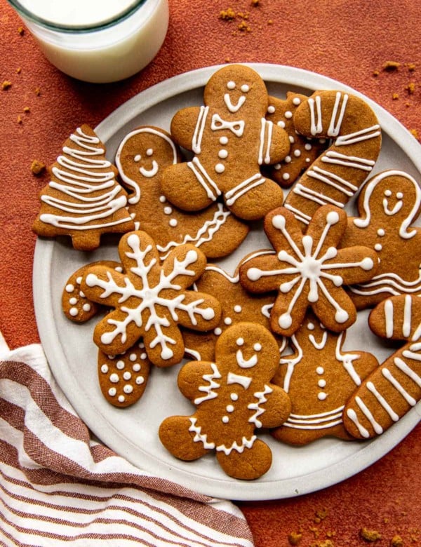 snowflake, tree, candy cane, and gingerbread men cookies with white icing on a white circle plate