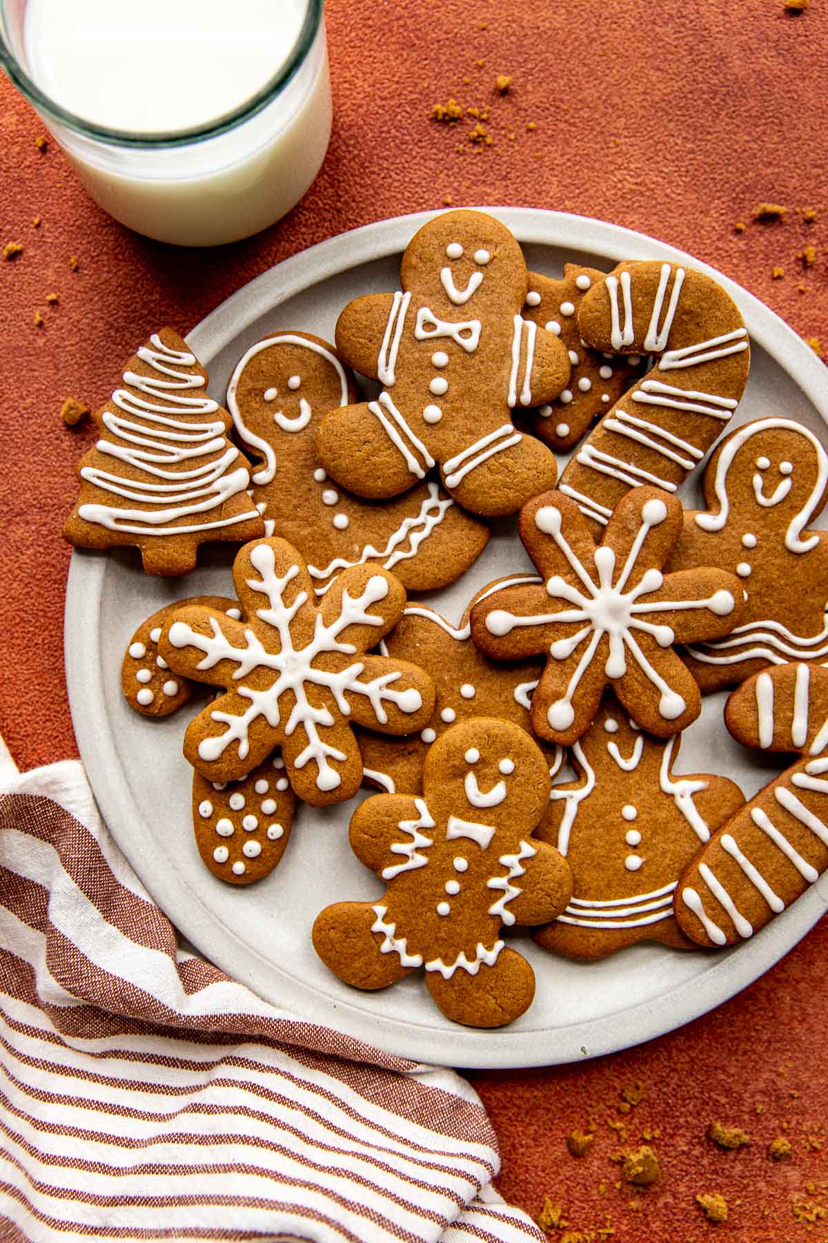 snowflake, tree, candy cane, and gingerbread men cookies with white icing on a white circle plate