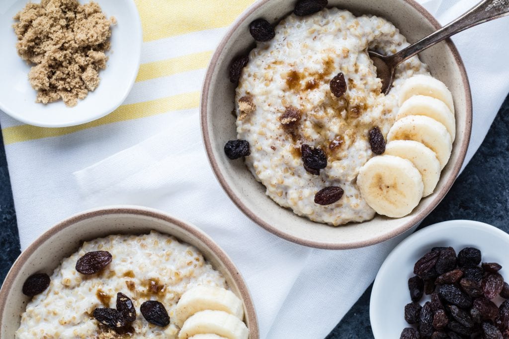 two bowls of instant pot steel cut oats topped with sliced banana and raisins