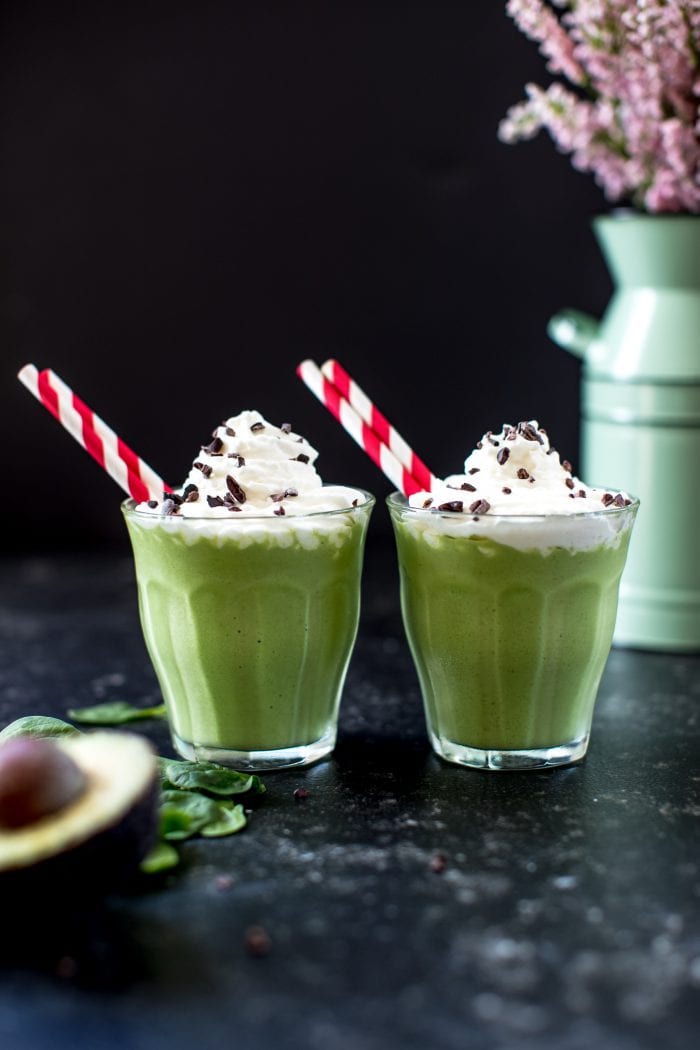 a green smoothie in a glass cup topped with whipped cream