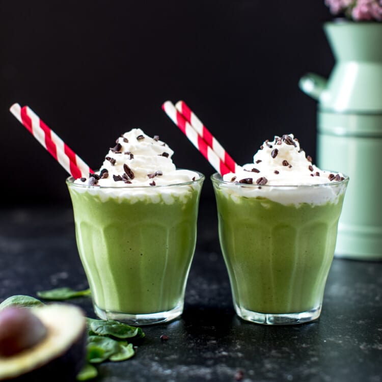 a green smoothie in a glass cup topped with whipped cream