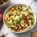 zoodle salad in a large white bowl with corn, tomatoes and kidney beans