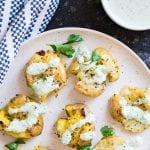 Smashed potatoes on a plate with a napkin and aioli on the side