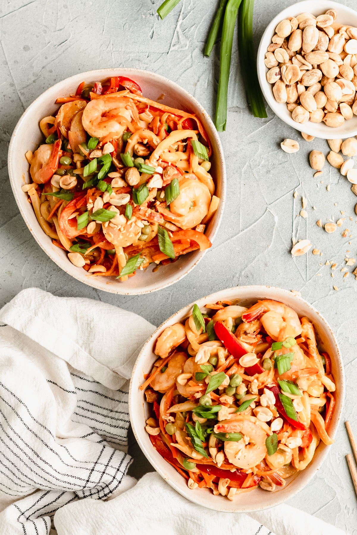 a white bowl filled with noodles and shrimp topped with green onions