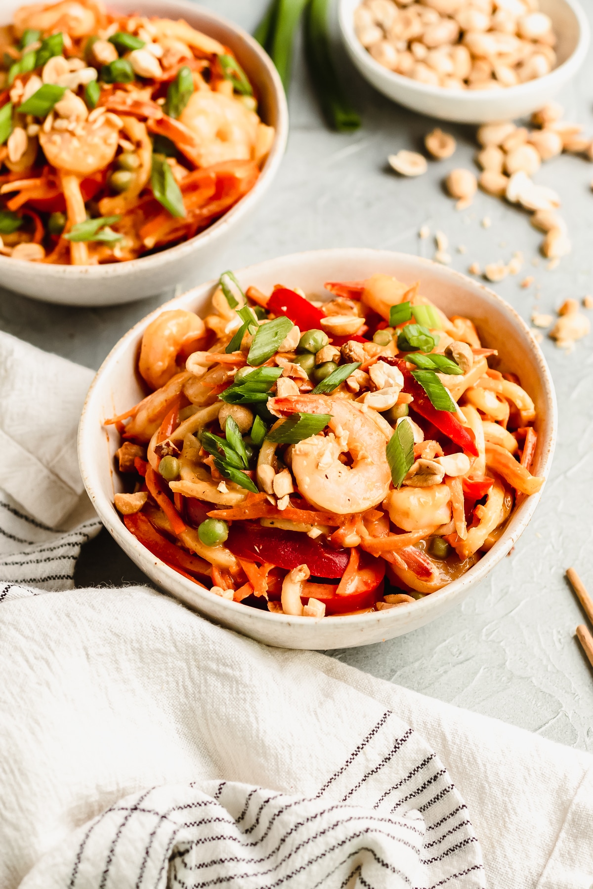 a white bowl filled with noodles and shrimp topped with green onions