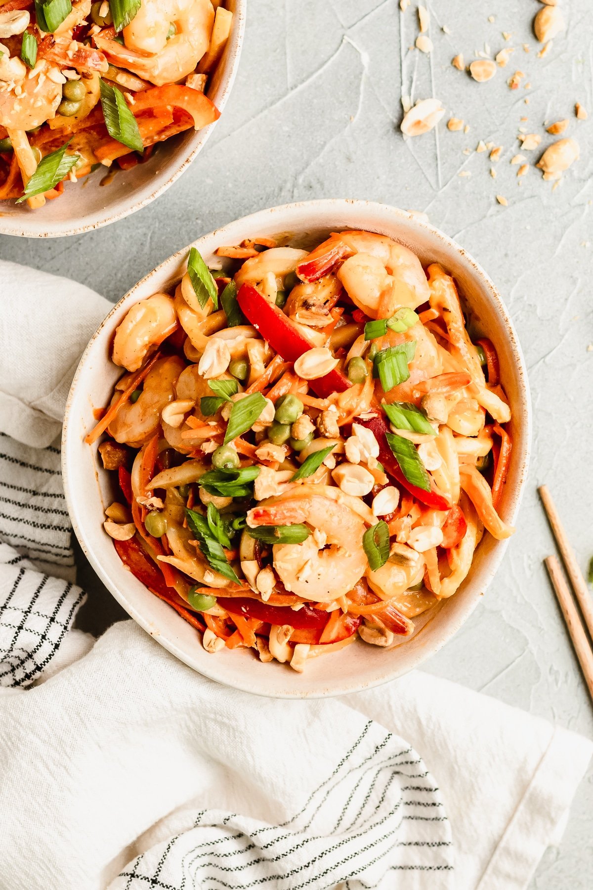 noodles in a white bowl with peanut sauce and shrimp garnished with green onions