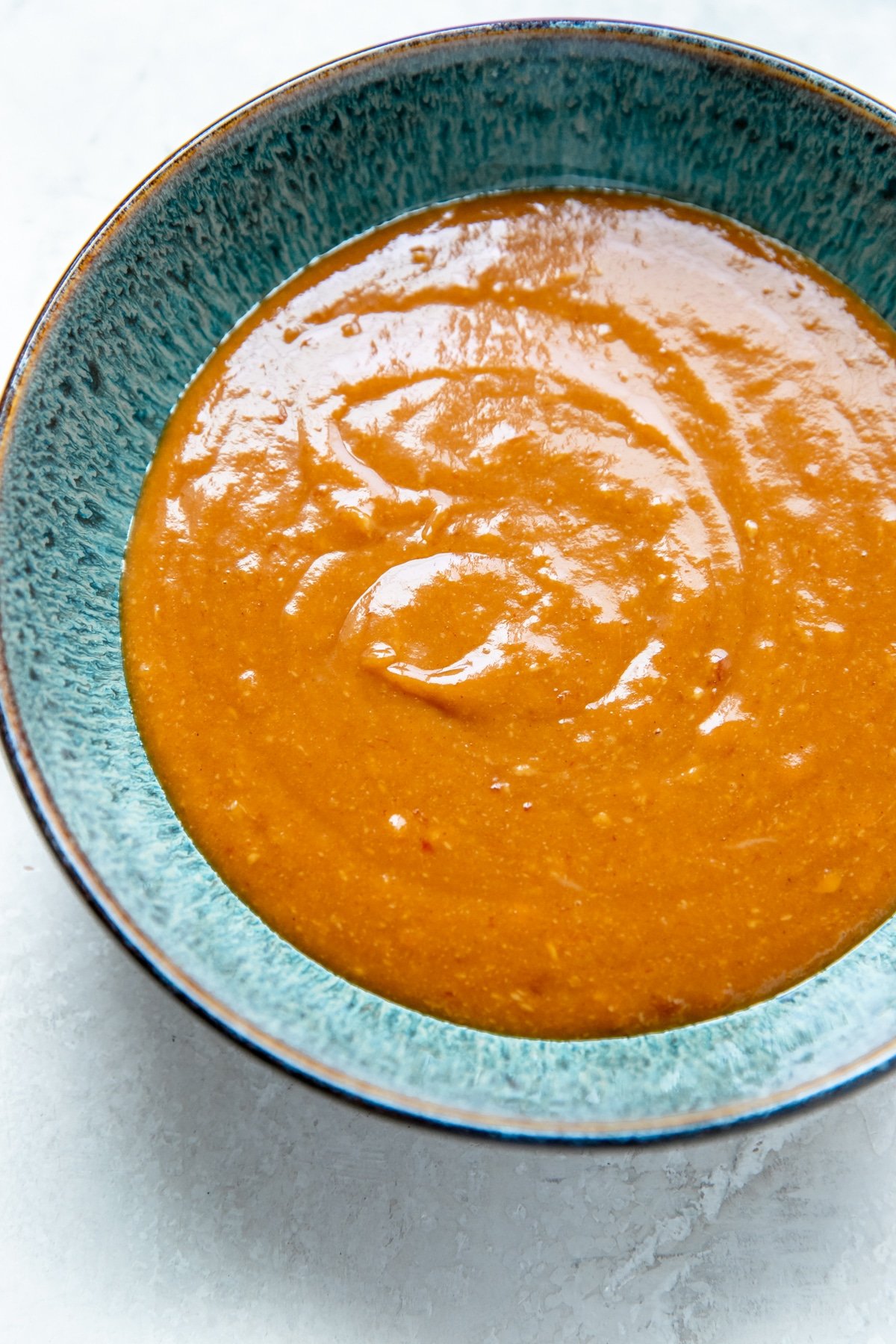 a blue bowl filled with thai peanut sauce
