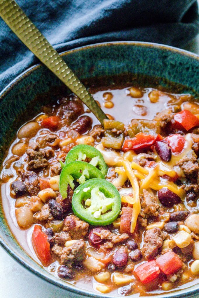 slow cooker lamb chili topped with jalapenos and cheese in a blue bowl