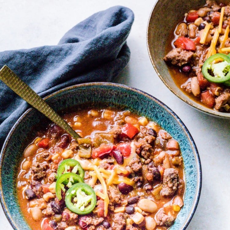 Lamb Chili in a bowl topped with jalapenos with a grey napkin on the side