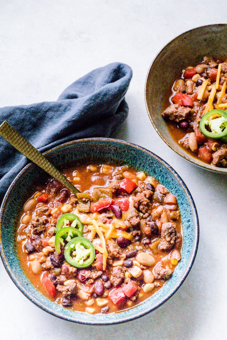 Lamb Chili in a bowl topped with jalapenos with a grey napkin on the side