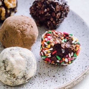 Chocolate Brownie Bites on a plate covered in different toppings like sprinkles and cocoa powder.