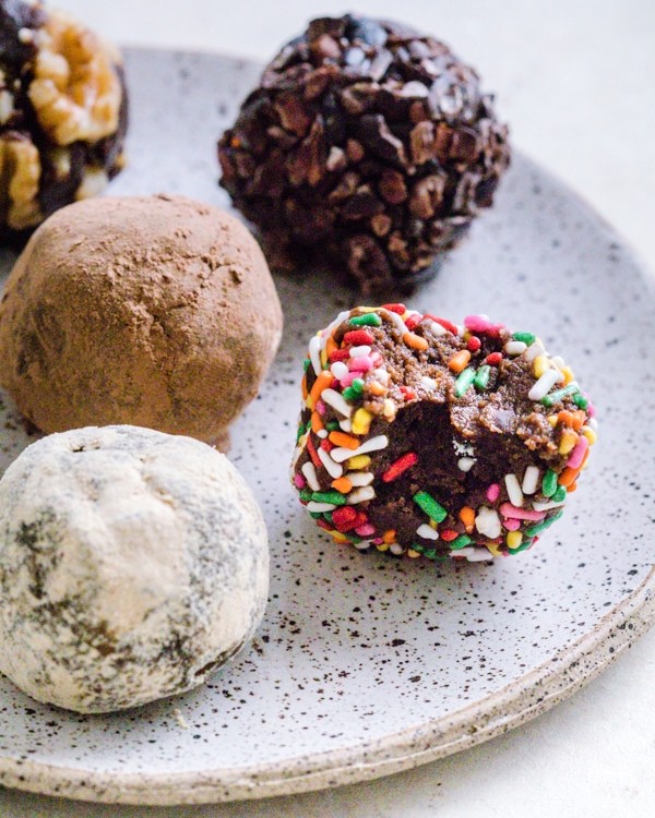 Chocolate Brownie Bites on a plate covered in different toppings like sprinkles and cocoa powder.