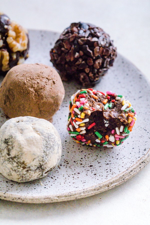 Chocolate Brownie Bites on a plate covered in different toppings like sprinkles and cocoa powder.