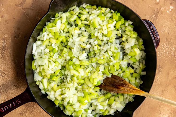 chopped onion and celery in a black cast iron skillet