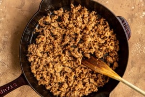 ground meat with wooden spoon in black cast iron skillet