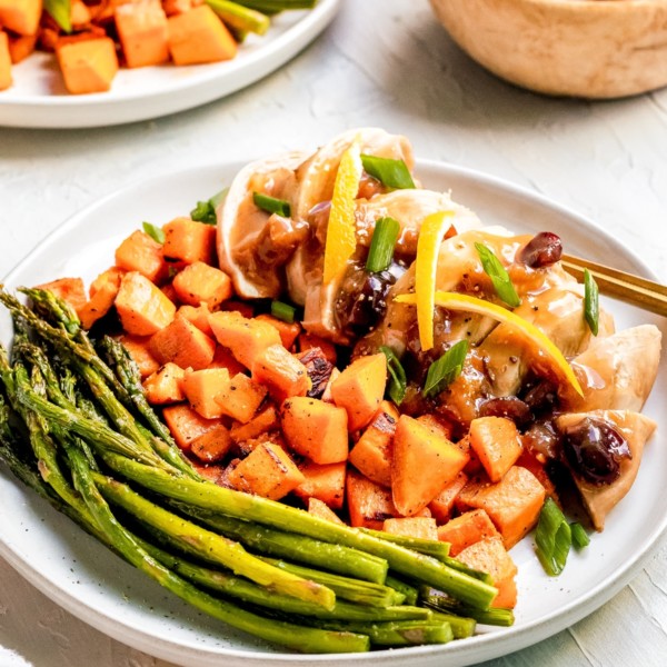 chicken on a white plate with veggies, cranberries and apricots