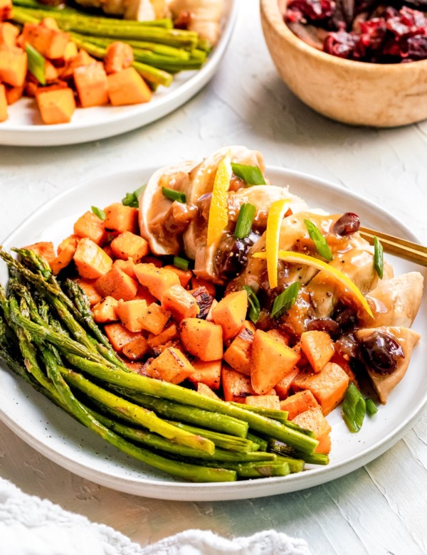 chicken on a white plate with veggies, cranberries and apricots