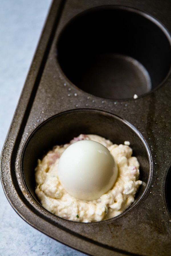 a hard boiled egg pressed in the middle of muffin batter