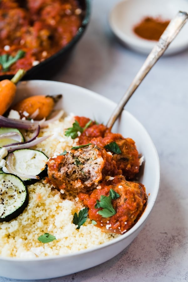 harissa meatballs with veggies and couscous in a white bowl