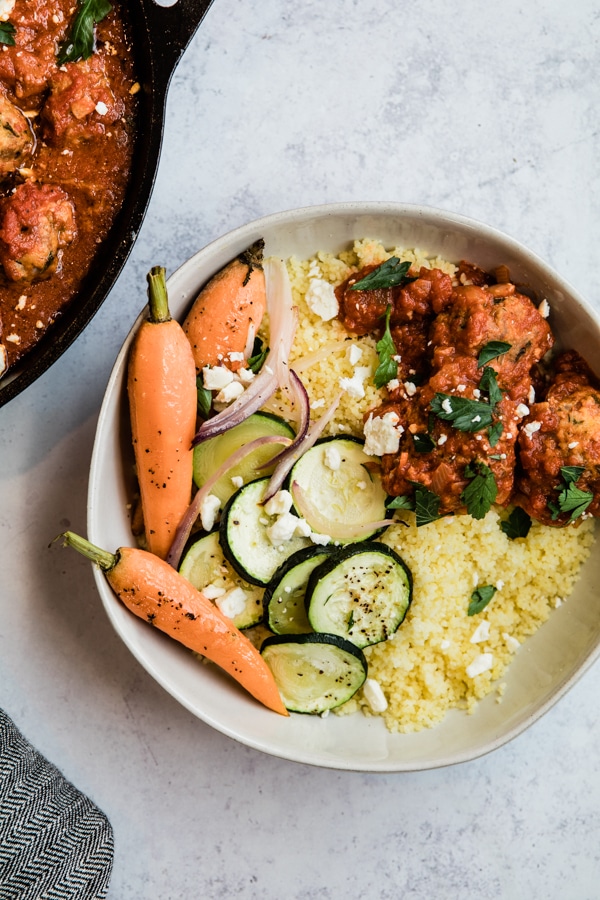 harissa meatballs with veggies and couscous in a white bowl