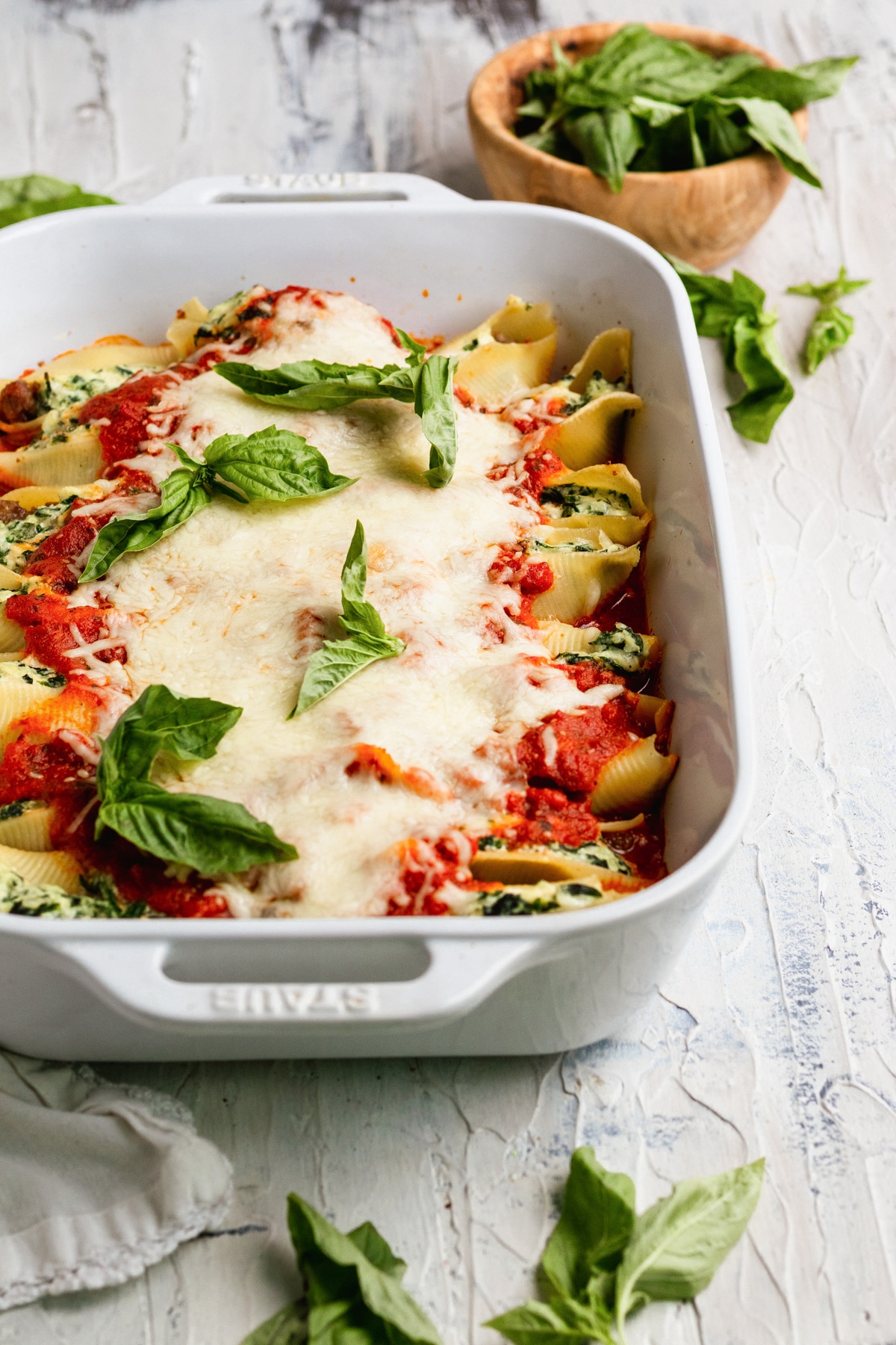 stuffed shells in a casserole dish topped with cheese and basil