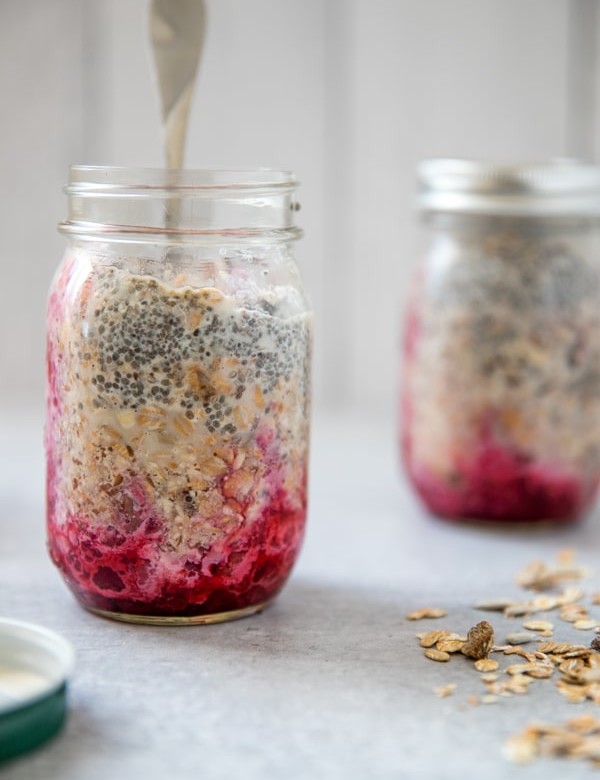 prepping overnight muesli in a mason jar with the fruit on the bottom