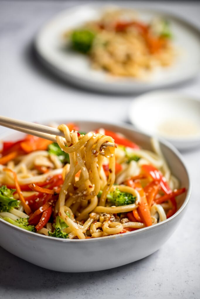 sesame udon noodles with veggies in a white bowl