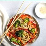 udon noodles being eating from a white bowl with chopsticks