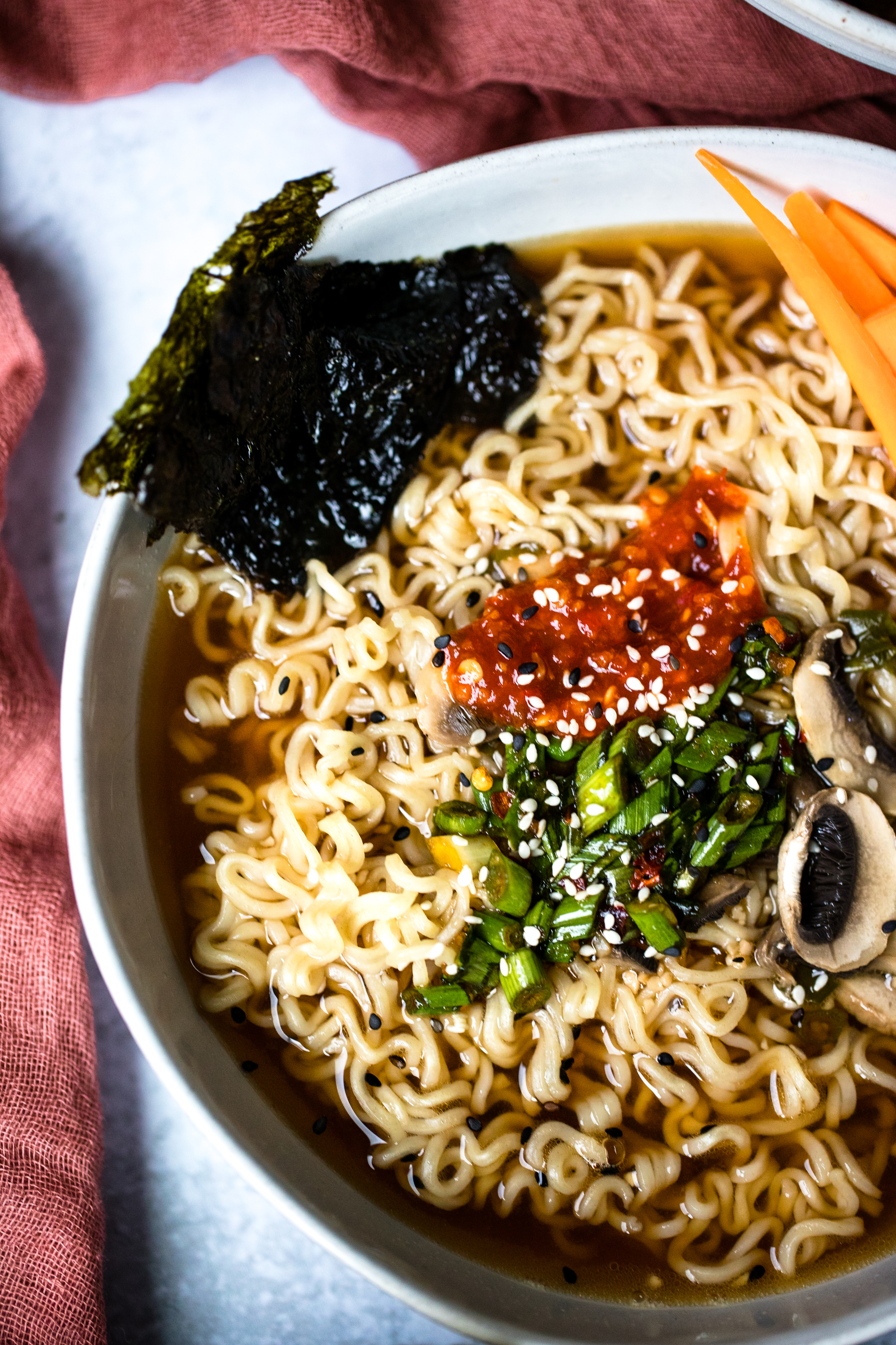 ramen noodles in a bowl with soft boiled eggs, carrots, mushrooms, and broth