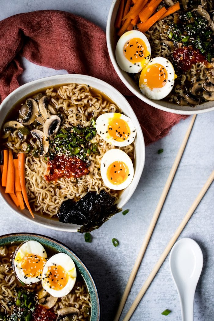 ramen noodles in a bowl with soft boiled eggs, carrots, mushrooms, and broth
