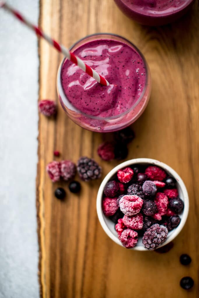 blueberry smoothie on a wood board with frozen fruit