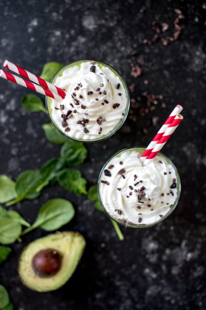 a green smoothie in a glass cup topped with whipped cream