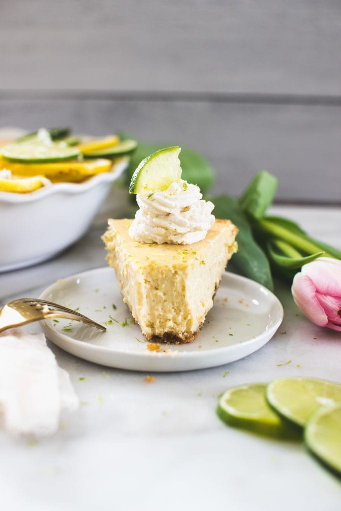 a slice of key lime pie on a white plate with whipped cream on top