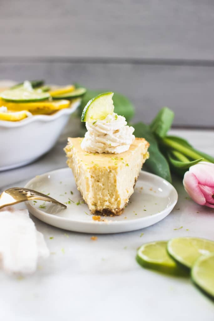 a slice of key lime pie on a white plate with whipped cream on top