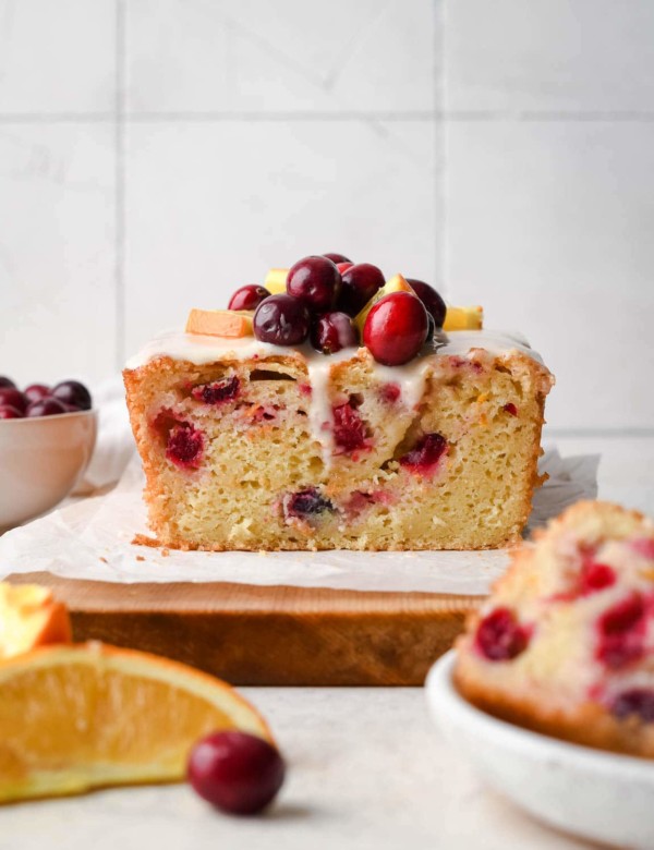 quick bread on a cutting board topped with cranberries