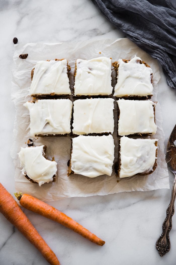carrot cake bars cut into squares on parchment paper